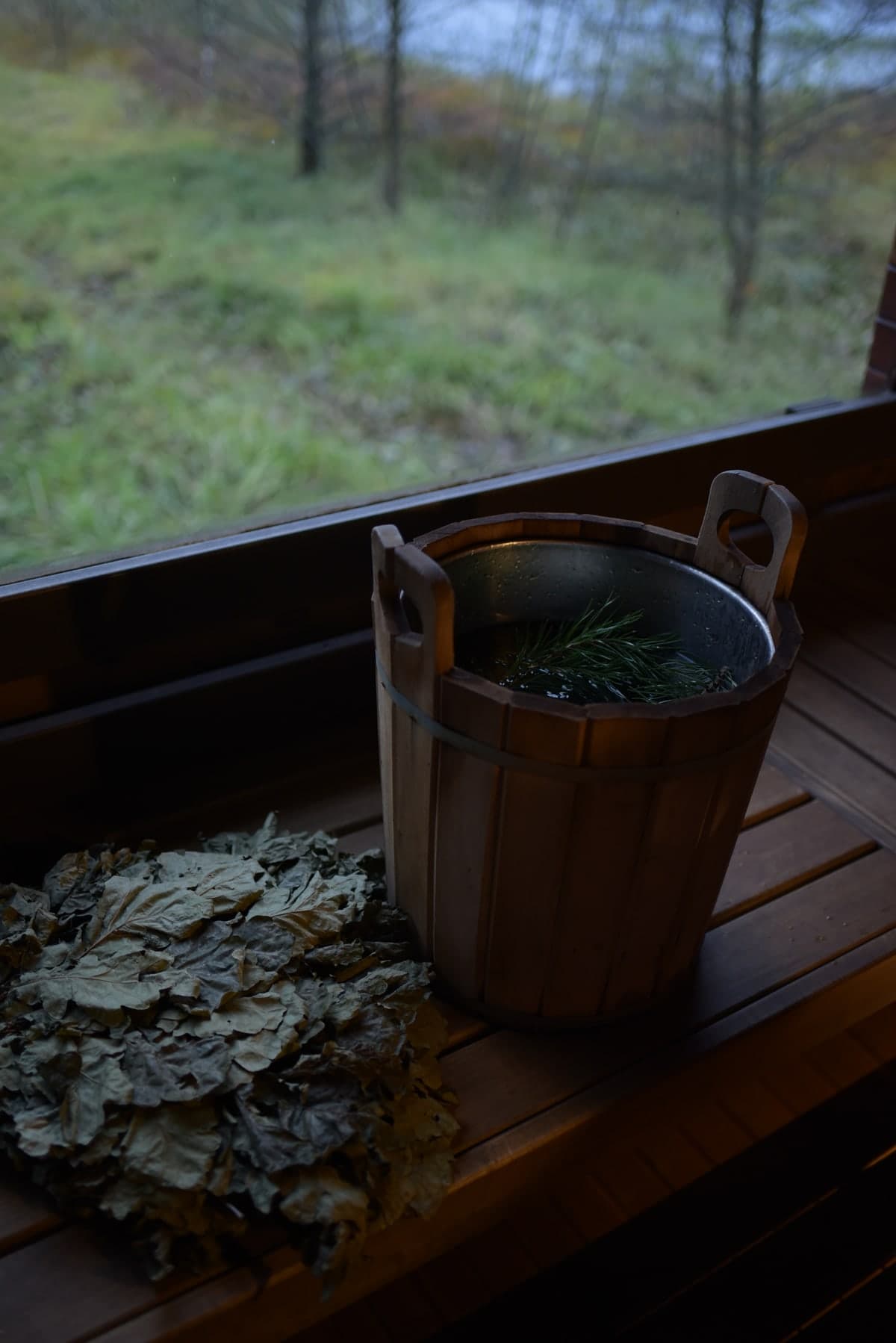 A wooden bucket with a spruce sprig and an oak besom by the window