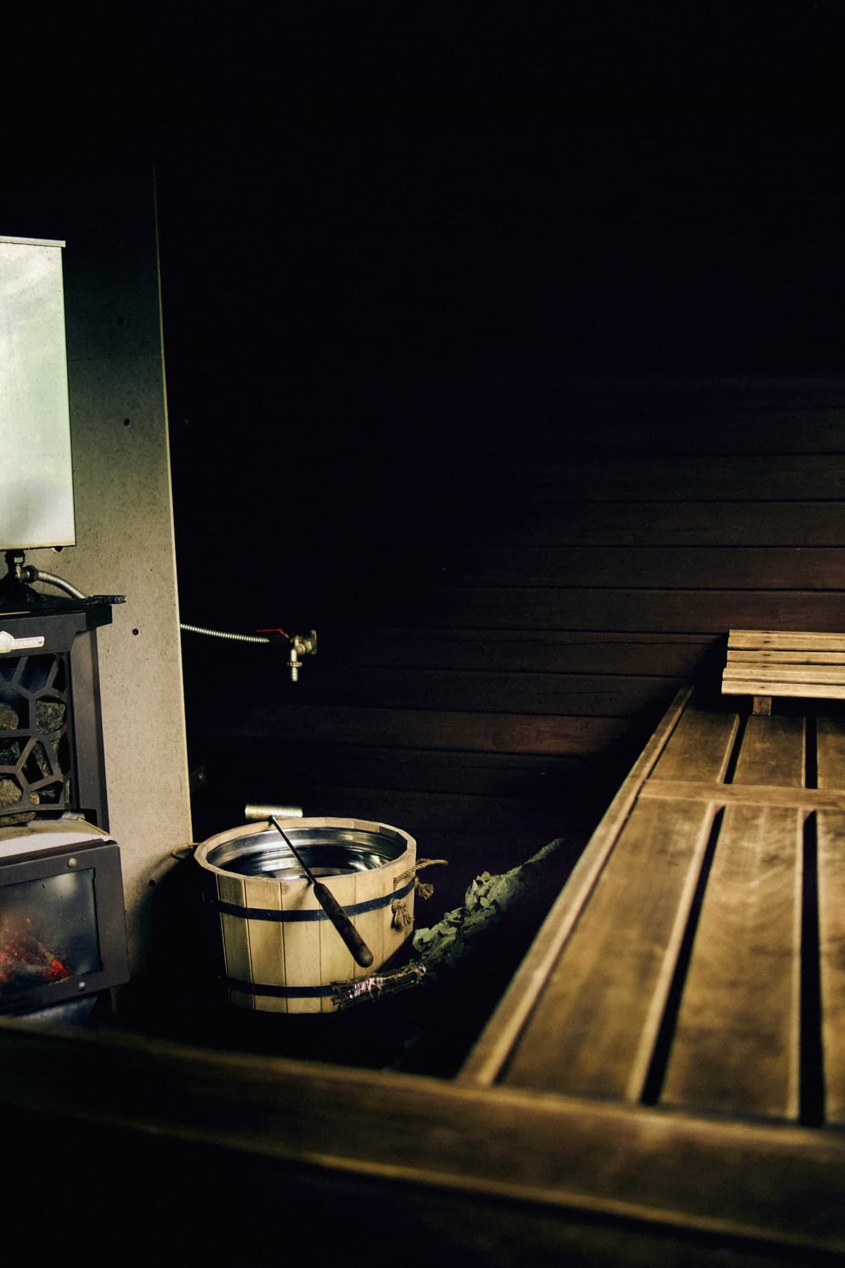 A stove with an open fire and a wooden bucket in the steam room