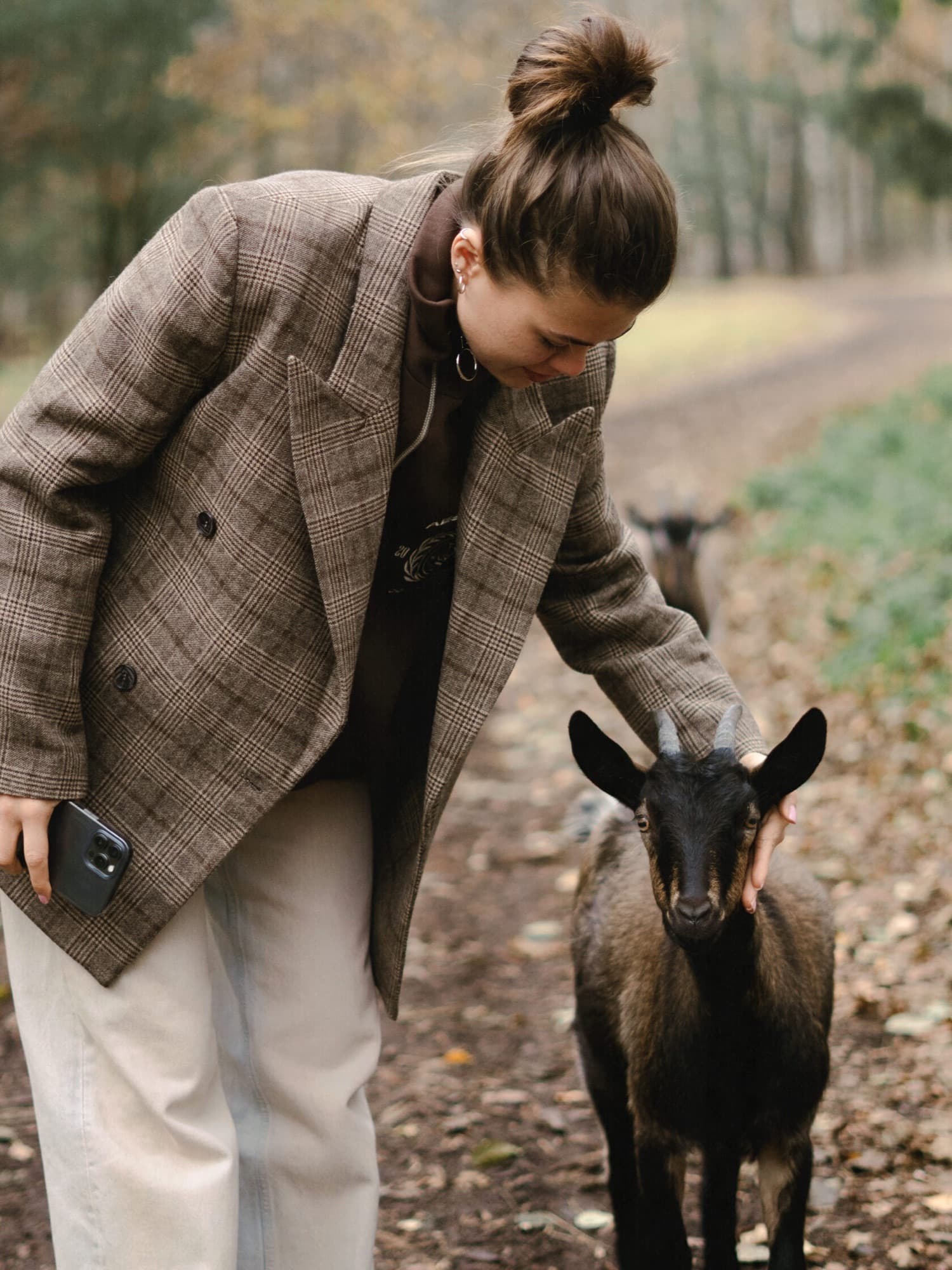 A woman stroking a young goat on a path
