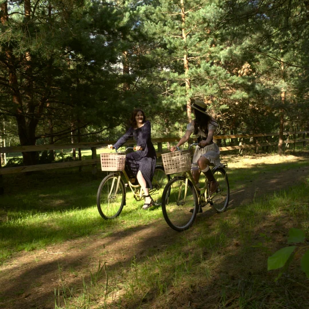 Two women cycling along a forest path
