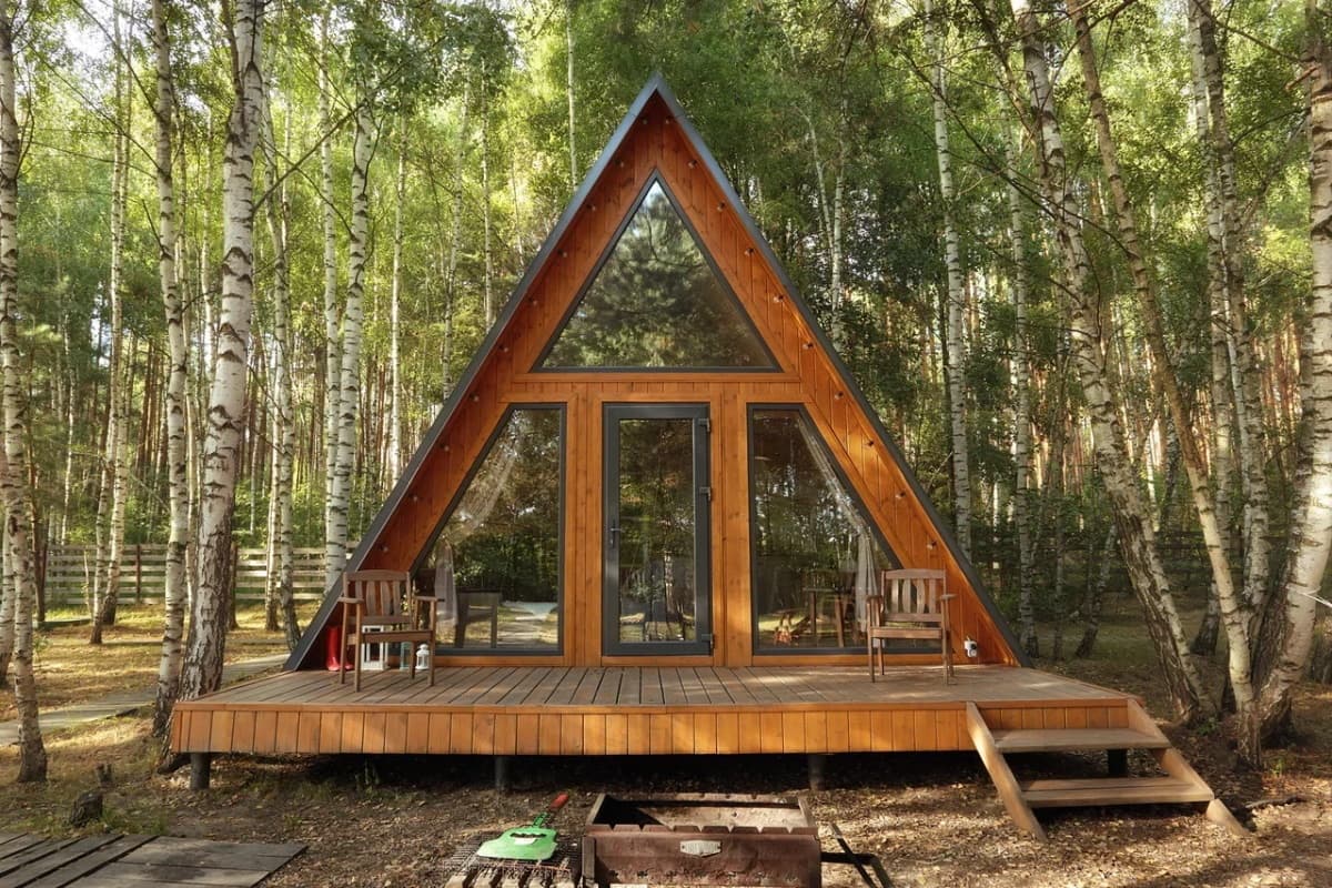 An A‑frame cabin with a terrace in a birch forest