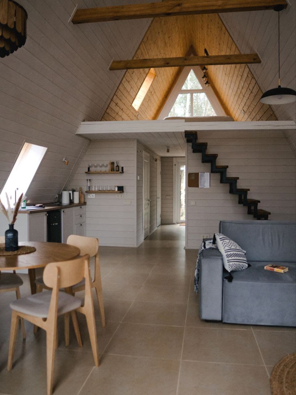 Living room of an A‑frame cabin with a kitchen and stairs up