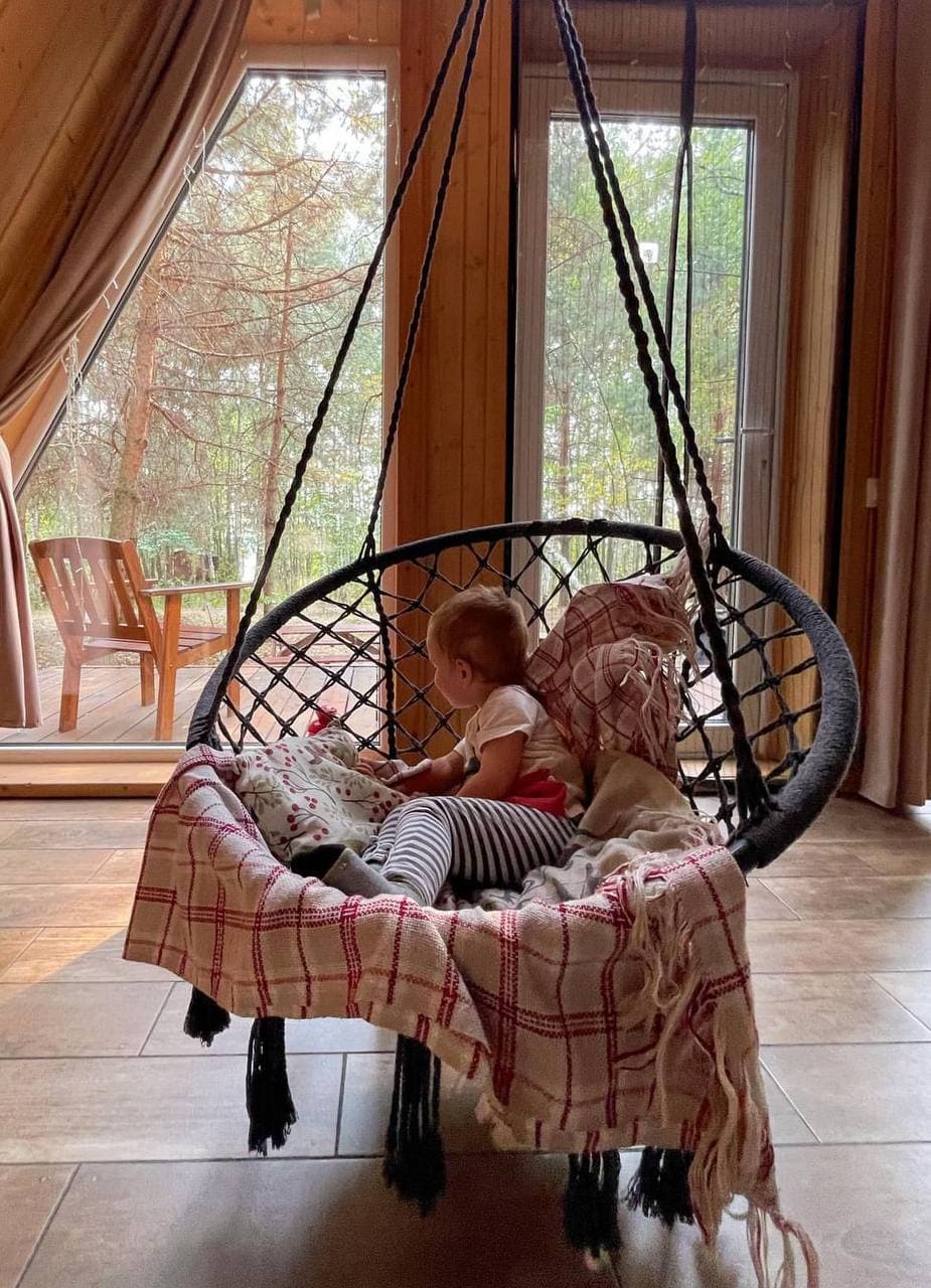 A girl in a hanging chair by the window