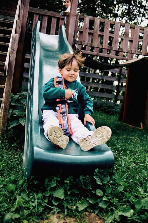 A boy coming down a green slide