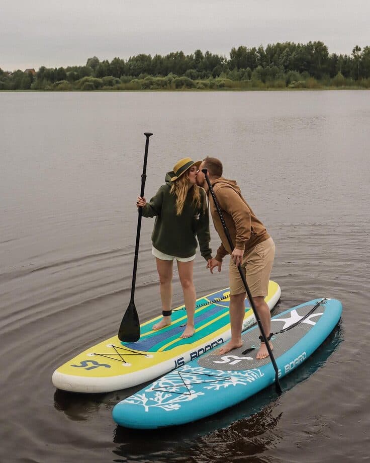 A couple kissing while standing on paddleboards