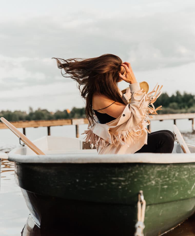 A woman with windblown hair in a boat by the pier