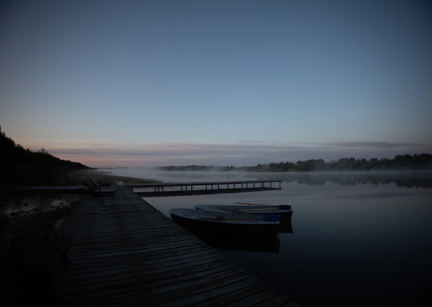A pier and boats in the morning mist