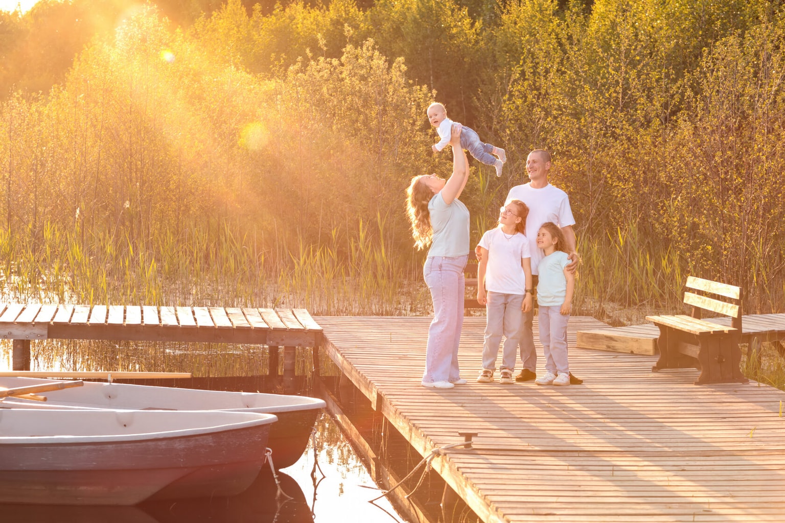 A family on a pier in the sunset light, a father lifting his baby